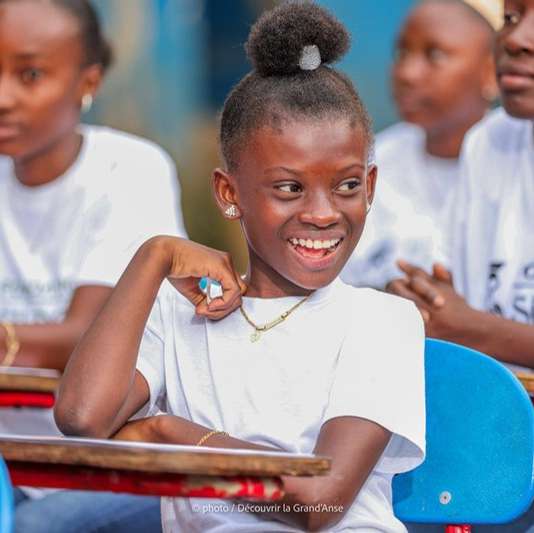 Une élève souriante en classe, parmi des jeunes portant le t-shirt de la Fondation Sildor